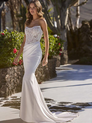 Enzoani - Love Eldora
£1,375ELDORA features a romantic silhouette crafted from stretch satin and exudes a dreamy aura, perfect for the modern bride seeking both sophistication and comfort. The scoop neckline delicately frames the collarbones, while buttons trailing down the train add a touch of whimsy to this sculptural design. ELDORA promises a heavenly blend of grace and charm for your special day.
Rail size UK18