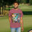 Thumbnail: burgundy tee shirt with a colorful beach and palm tree image with an old Corvette and an older guy wearing a Hawaiian shirt