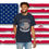 Thumbnail: black colored T-shirt with a circular American flag printed the center with "America"  above "Land of The Brave" below