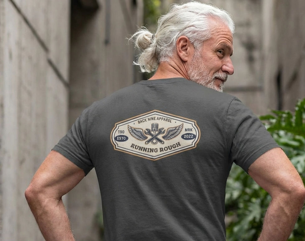 Gray tee shirt worn by a middle aged male printed on the back of the Tee is a retro automotive logo design in tan and blue