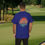 Thumbnail: blue t-shirt Old Dudes Club over a beach theme circular back ground