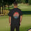 Thumbnail: black t-shirt Old Dudes Club over a beach theme circular back ground