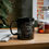 Thumbnail: Black coffee mug with a gray western theme Wild Wild West Printed above and Old Dudes Club below