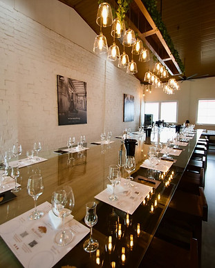 Long wooden table set with wine glasses and tasting mats for a guided wine tasting. The soft lighting creates an elegant ambiance. 