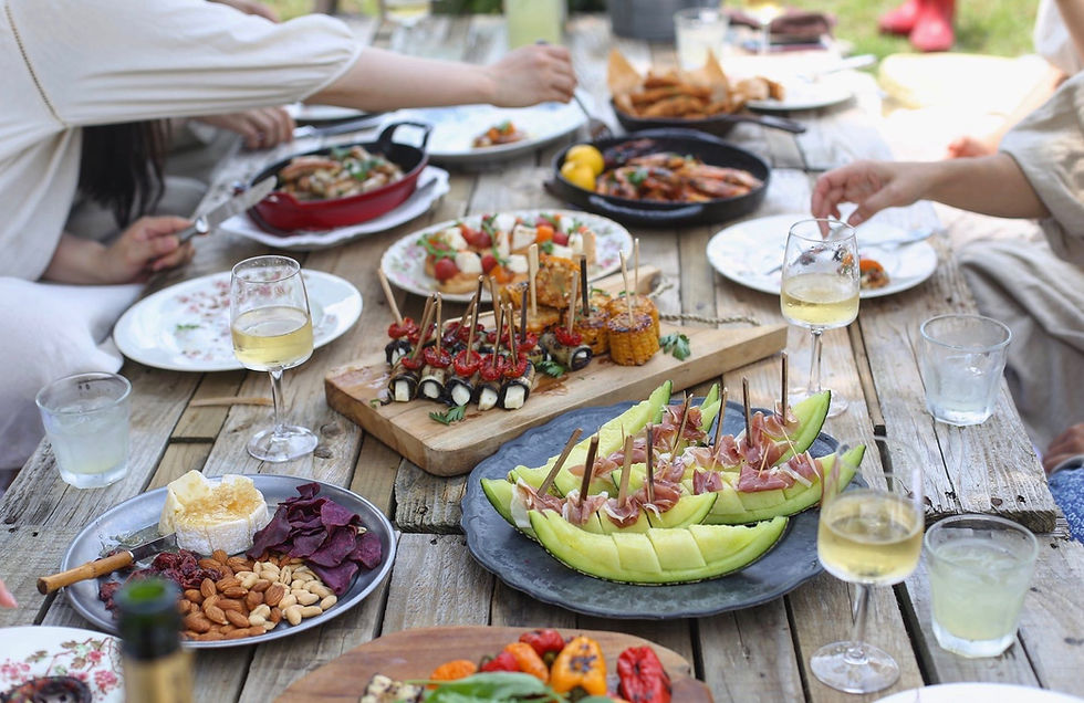 People enjoying a variety of colorful foods and white wine glasses laid on a wooden table
