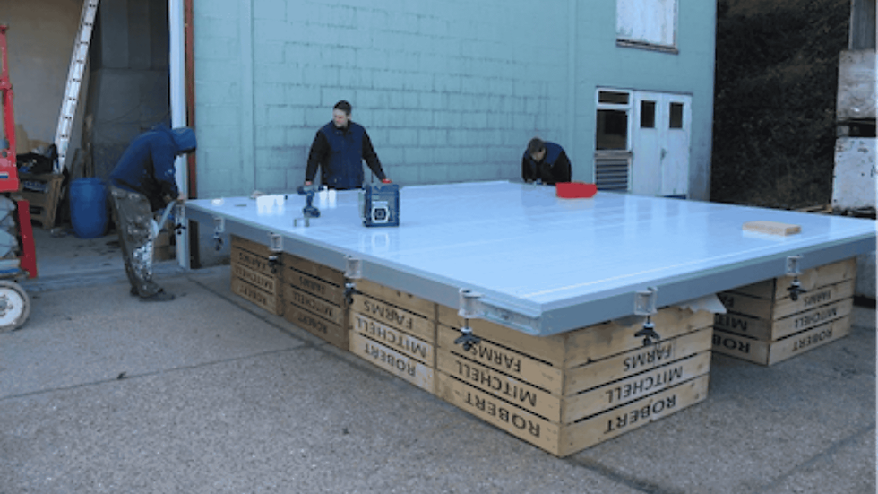 Three men work on large door outside the storage unit. The door is balanced on large apple crates