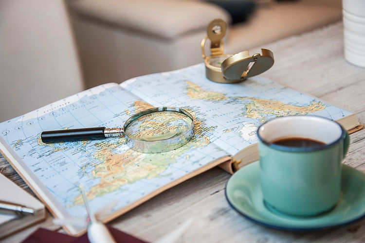 planning a new travel adventure with coffee, map, compass and magnifying glass on a wooden