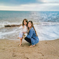 IMG_20200721_193528_3.jpegMia crouches on the beach with her young daughter, both smiling at the camera with the sea and behind them.