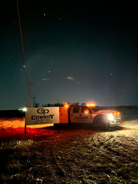 Cowboy Painting Co. fleet truck parked next to the company sign, highlighting our professional branding and readiness for any commercial or industrial painting project.