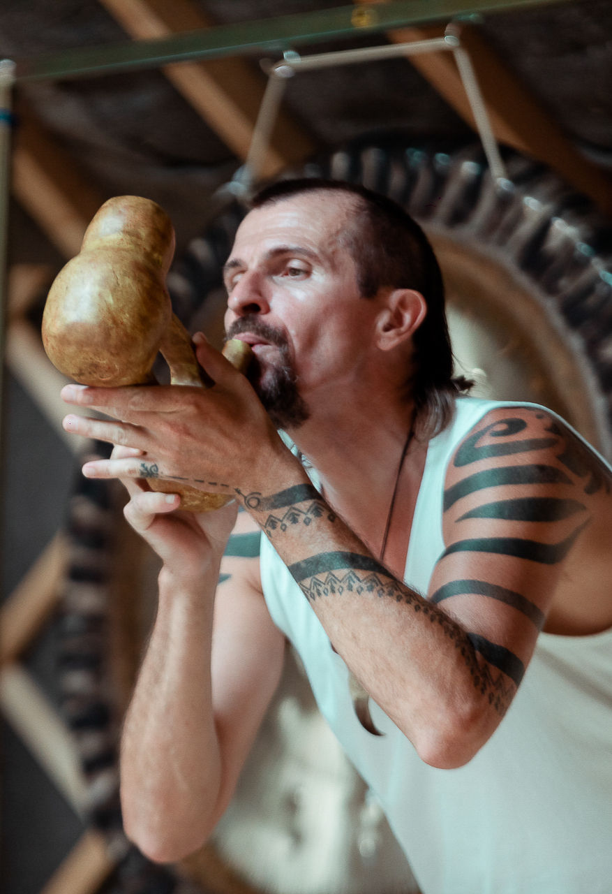 Tom, an indigenous instrument teacher, is blowing into a water whistle, which is a clay funerary object that has two chambers