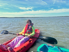 Child sitting on a kayak holding a paddle