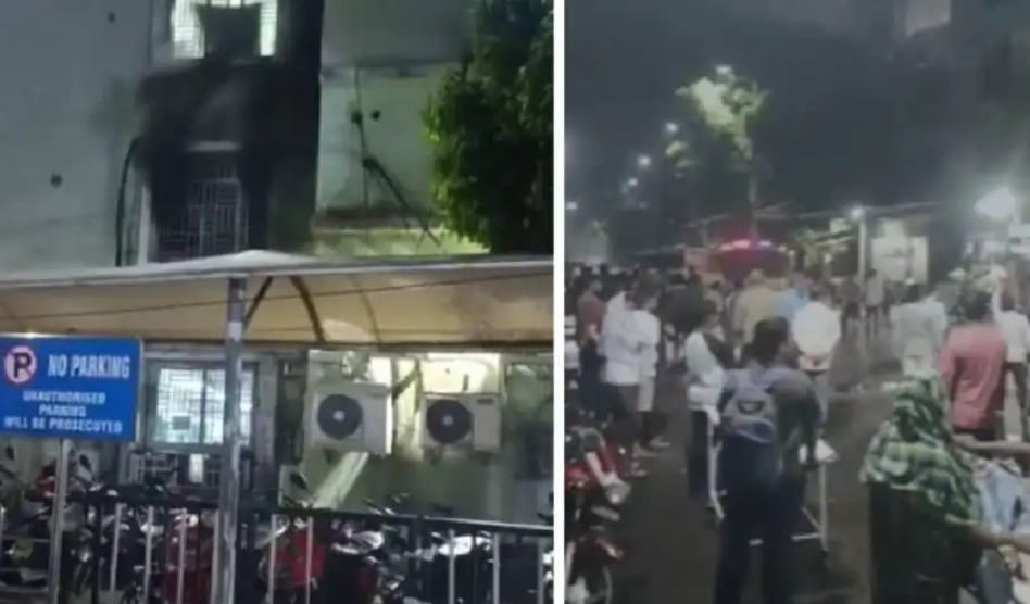 Building with black smoke damage, crowd gathered at night