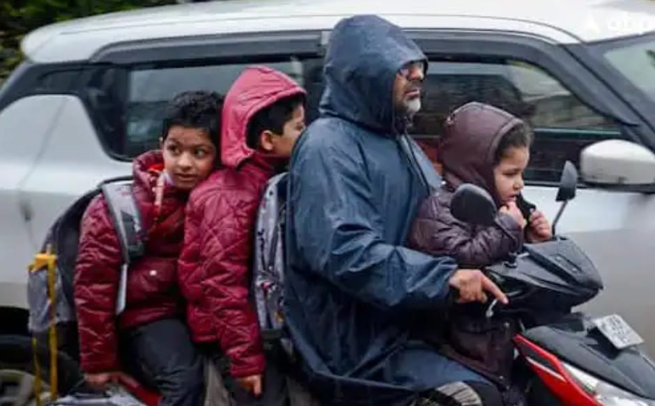 Four people on a scooter dressed for rain