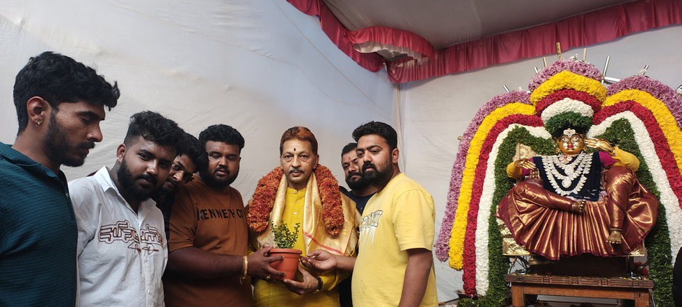 Man in garland with plant, men around, decorated deity