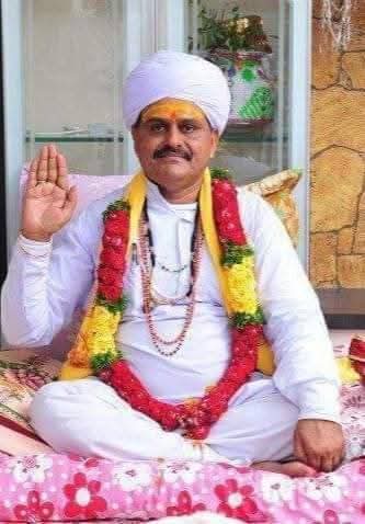 Spiritual leader in white turban and garland raising hand