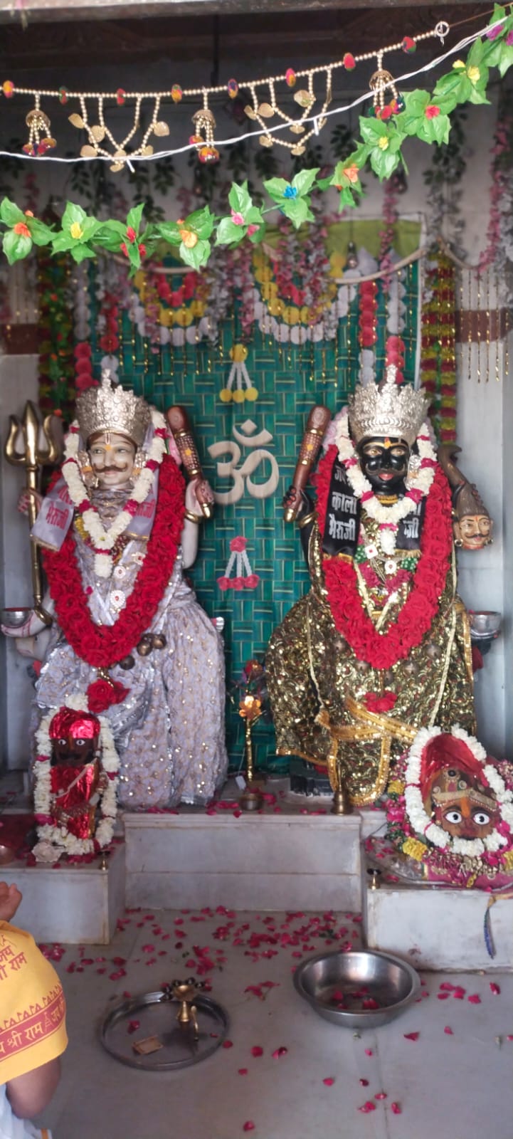 Two decorated idols with red garlands in a Hindu temple.
