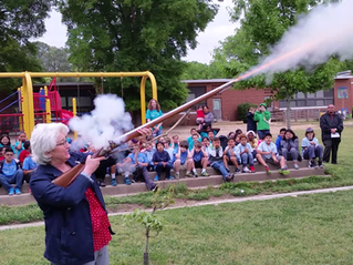 A teacher shoots a flintlock rifle at a Camp Flintlock Field Trip