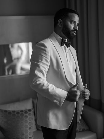 Groom wearing a white dinner jacket and adjusting his suit during wedding preparations at Palácio do Freixo in Porto, Portugal.