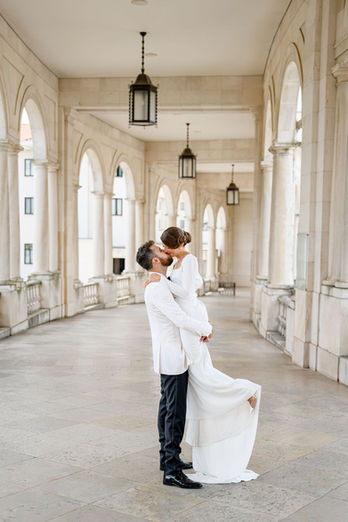 After the ceremony at the Sanctuary of Our Lady of Fátima, the groom lifts the bride into his arms as they share a passionate kiss, a joyful and spontaneous celebration of their newlywed moment