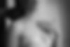Close-up of the bride's neck showing her pearl necklace and the wedding ring on her hand, which is touching the necklace.