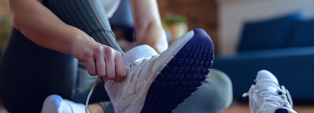 eine sportliche Frau zieht sich Turnschuhe an
