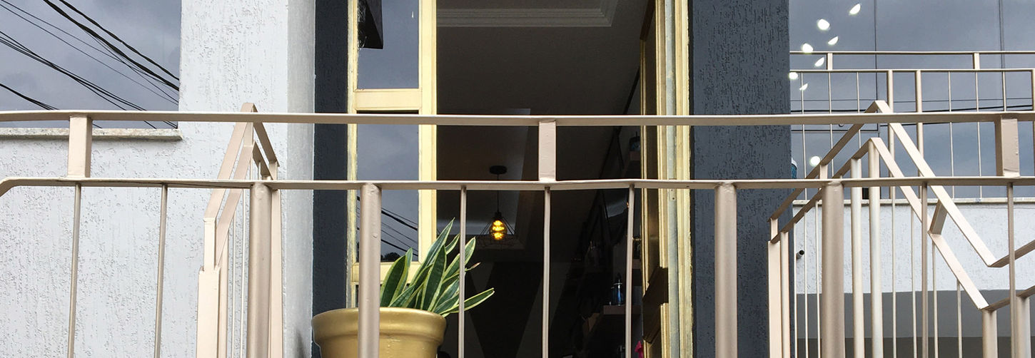 Entrada do salão de beleza Studio W Neves com porta de vidro emoldurada em dourado e vaso decorativo na sacada.