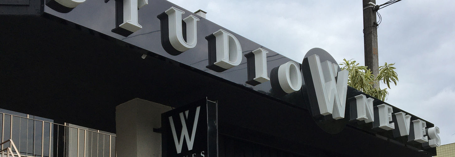 Fachada do Studio W Neves com letreiro em relevo branco sobre painel preto, destacando o design comercial moderno.