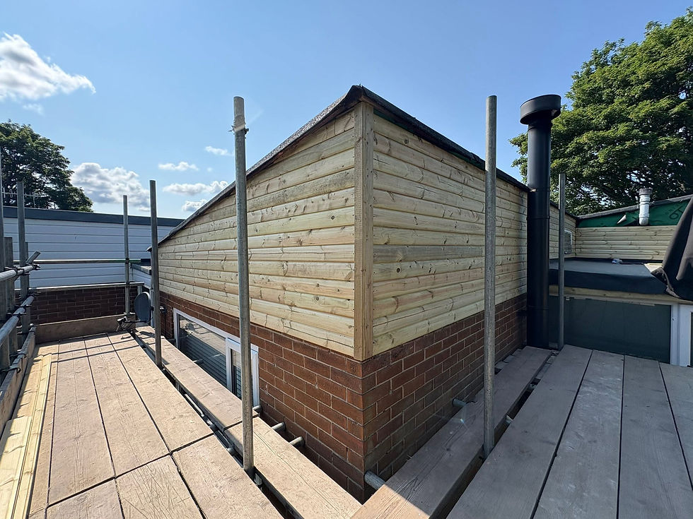 Building exterior with timber cladding over brick base, viewed from scaffolding platform