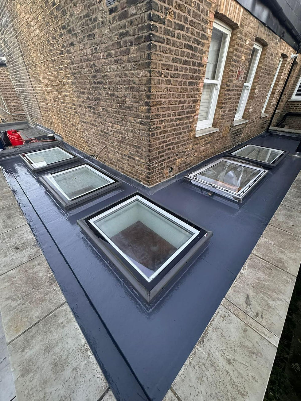 Flat roof with four glass skylights beside a brick building exterior