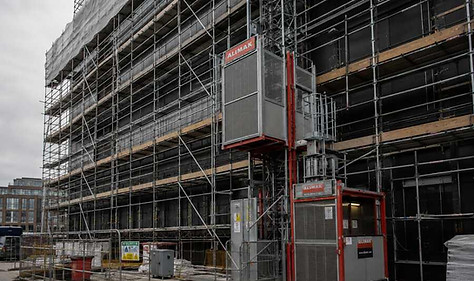 Alimak construction hoist attached to scaffolding on a building under construction