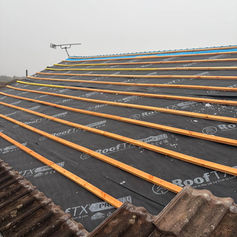 Black breathable roofing membrane and timber battens laid out across a pitched roof