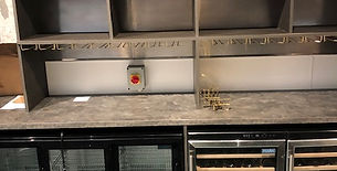 Commercial bar setup with refrigerated wine storage and empty shelving above
