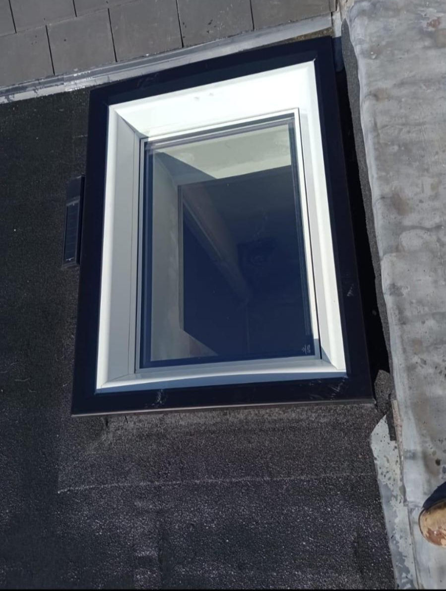 Flat roof skylight with dark frame installed on a felt roof