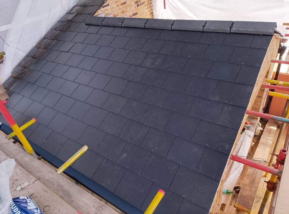 Newly laid dark slate roof tiles on a building under construction with scaffolding