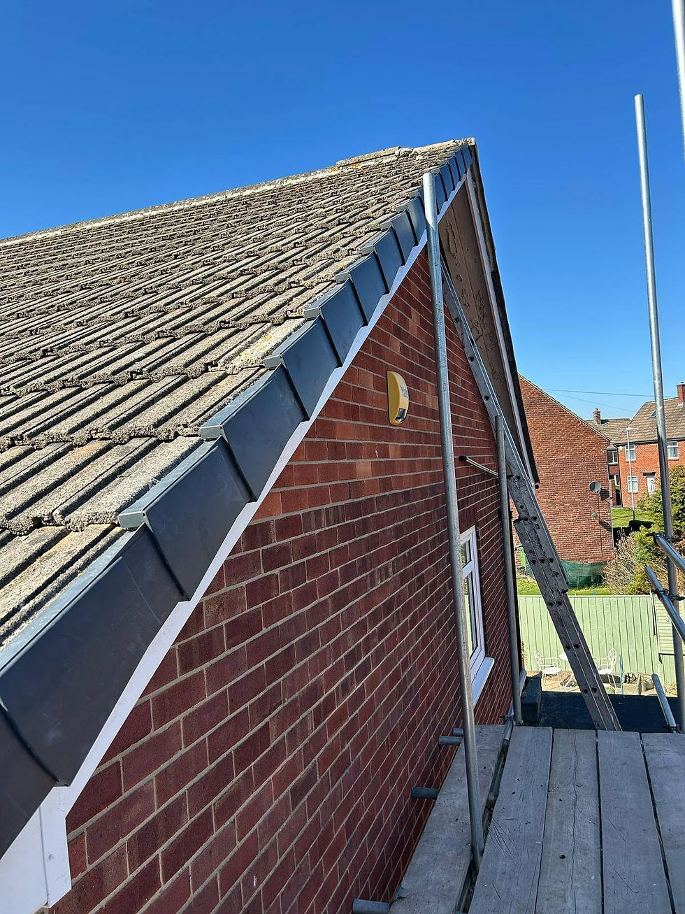 Brick house gable end with new grey fascia and soffit installation on scaffolding