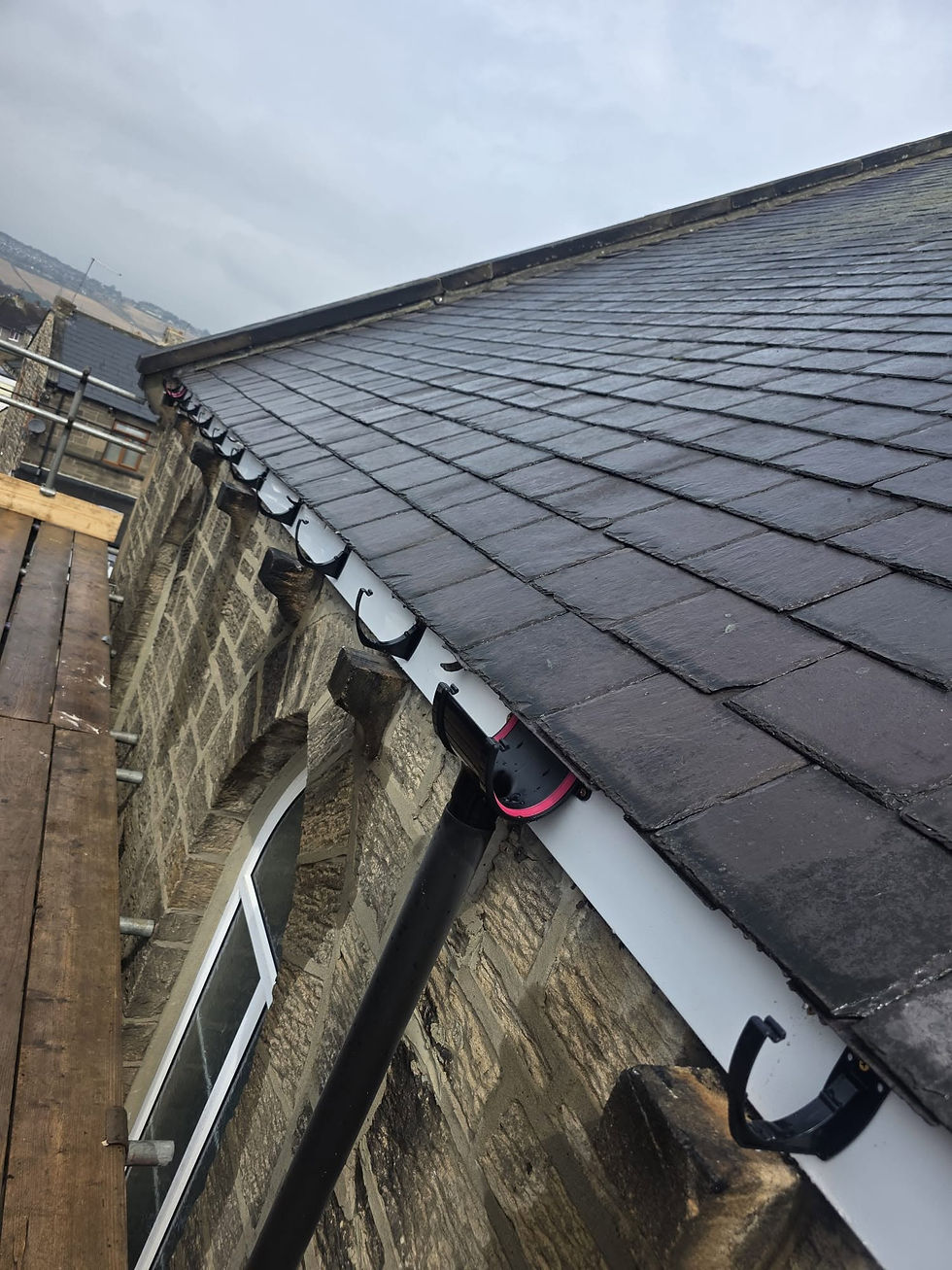 Slate roof with white guttering on a stone-walled building