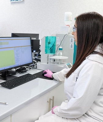 Scientist in white lab coat reviewing chromatography data on a computer monitor