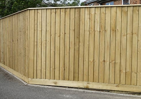 Tall wooden privacy fence with vertical boards along a residential pavement
