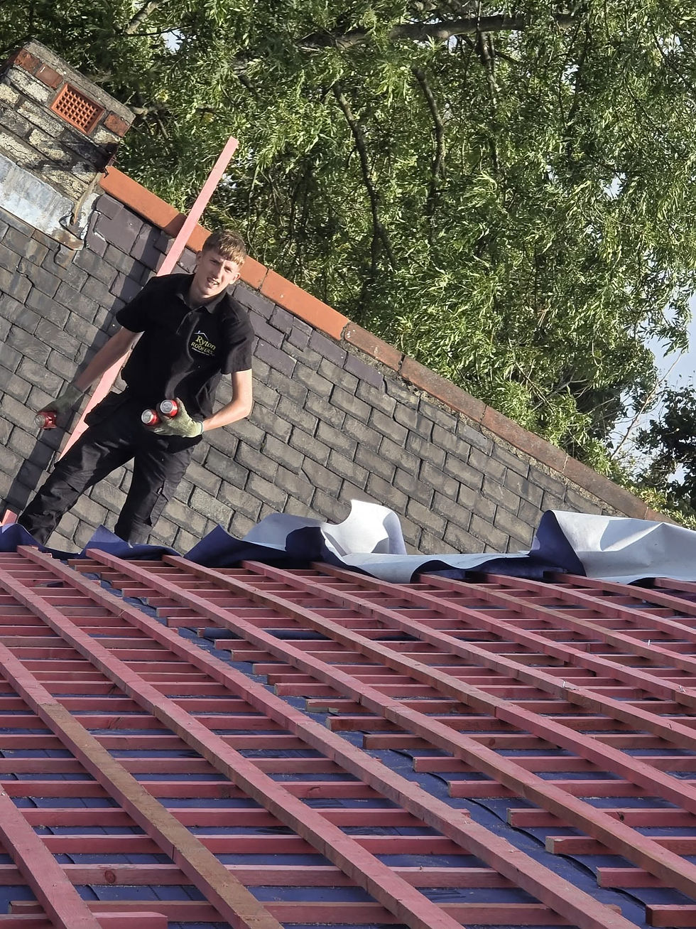 Roofer standing on a roof with exposed battens and felt underlay