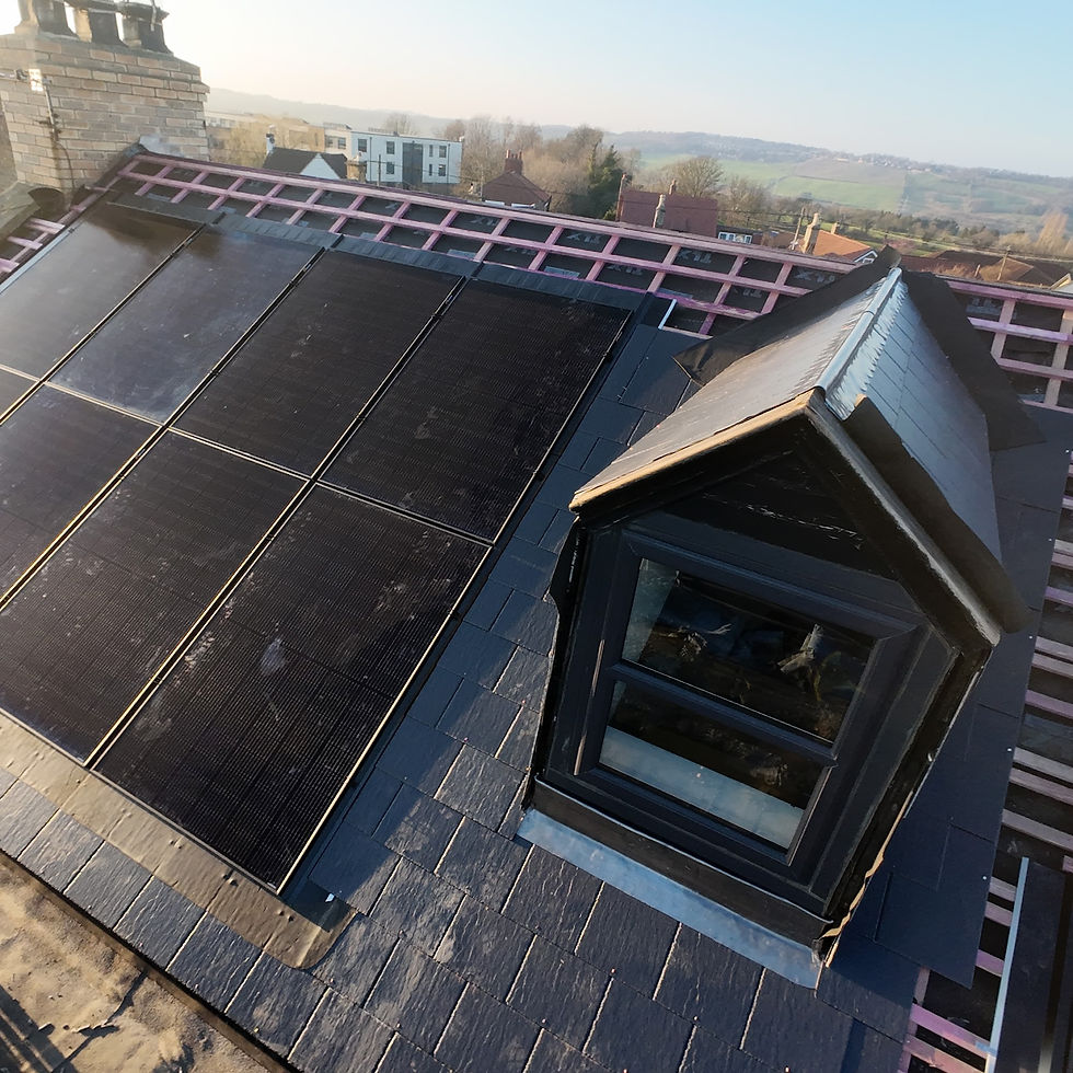 Solar panels on a slate roof with a dormer window, town visible beyond