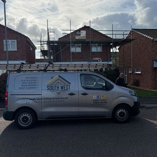 Silver roofing contractor van parked in front of a residential house with scaffolding