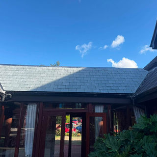 Slate pitched roof installation above a timber-framed conservatory entrance