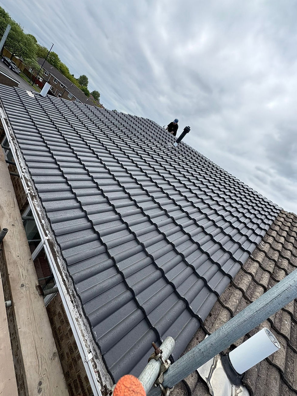 Roofer working at the ridge of a newly tiled grey roof with scaffolding