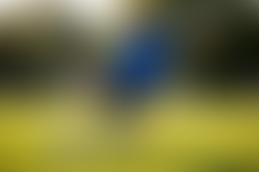 Λάκτισμα στο ποδόσφαιρο: έφηβος ποδοσφαιριστής με μπλε φανέλα και μαύρο σορτς σουτάρει σε γήπεδο