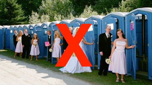 Luxury restroom trailer set up beside a landscaped garden and paved outdoor event area.