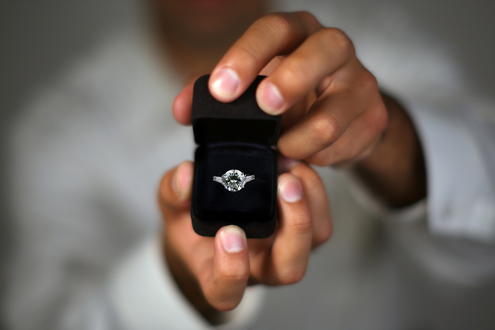 man holding ring box with a wedding ring imside