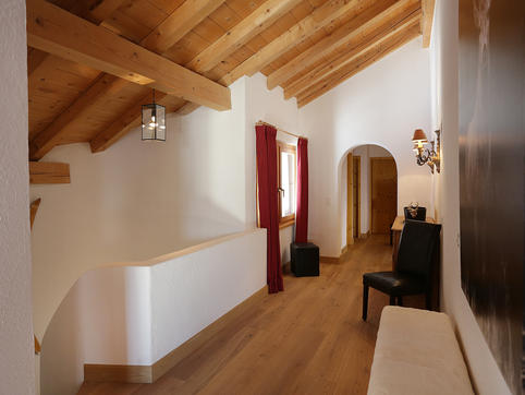 Upstairs chalet hallway with sloped wooden ceiling, arched doorway and natural light