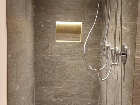 Walk-in shower with grey tiles and niche lighting in luxury chalet