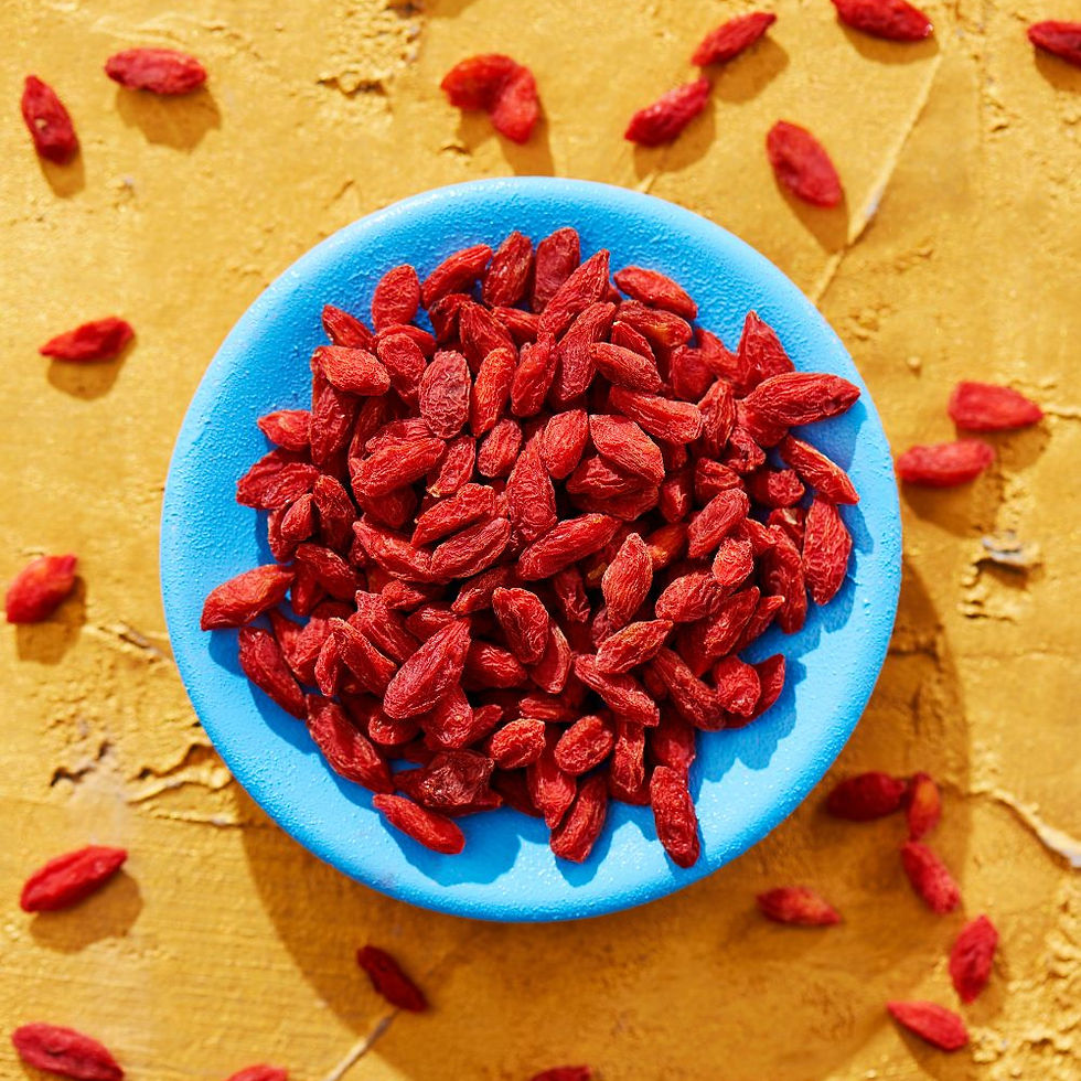 A bright blue bowl of dried wolfberries (also known as goji berries) on a bright yellow concrete table.