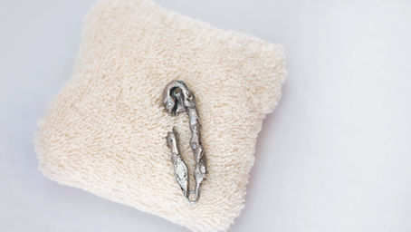 A soft, minimalist, fluffy handmade white brooch with terry toweling texture and a pin adorned with soft soldering designed and handmade by Megan Kennedy of PEURL Designs. The brooch is positioned on a plain white background. 